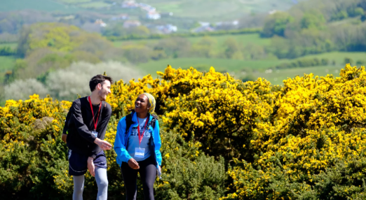 A man and woman smiling and talking whilst walking through countryside