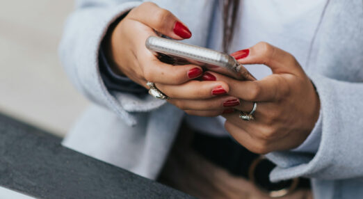 Close up of a woman's hands holding and typing on her phone