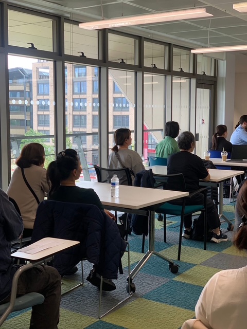 A group of women sat at desks, facing away from camera
