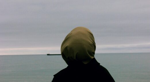 Woman facing away looks out to sea