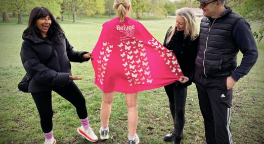 Refuge ambassadors stand with Hetti, who is facing away to show her pink cape with butterflies in a park